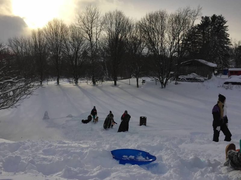 A group of people in the snow with sleds.