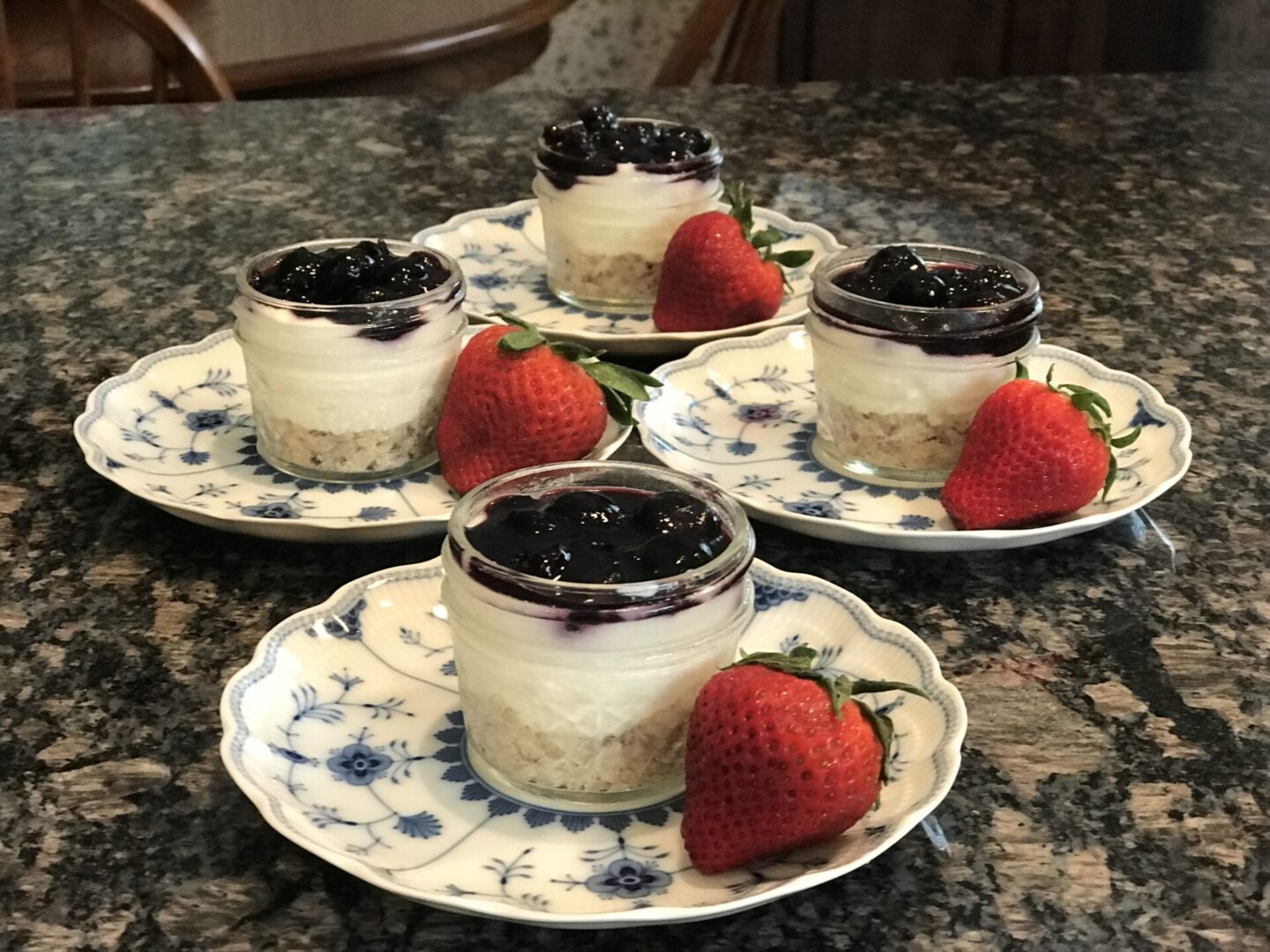 A group of four plates with some strawberries and jars.