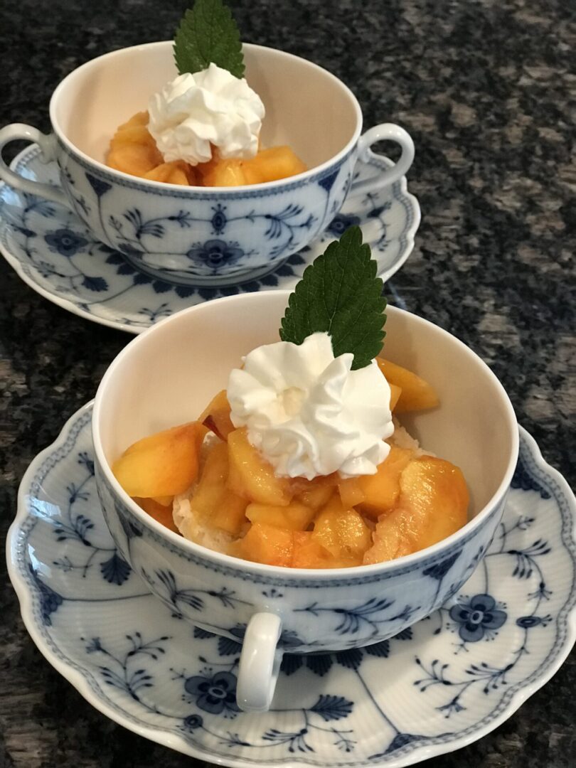 Two bowls of fruit with whipped cream on a table.