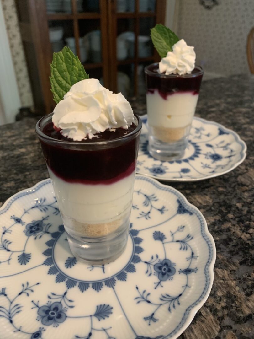 Two glasses of dessert on a blue and white plate.