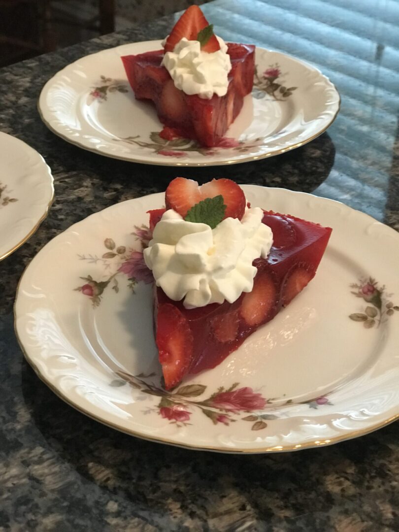 Two plates with strawberries and whipped cream on them.