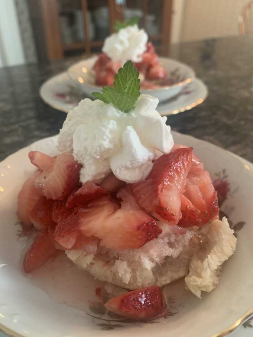 A plate of strawberries and whipped cream on top of a table.