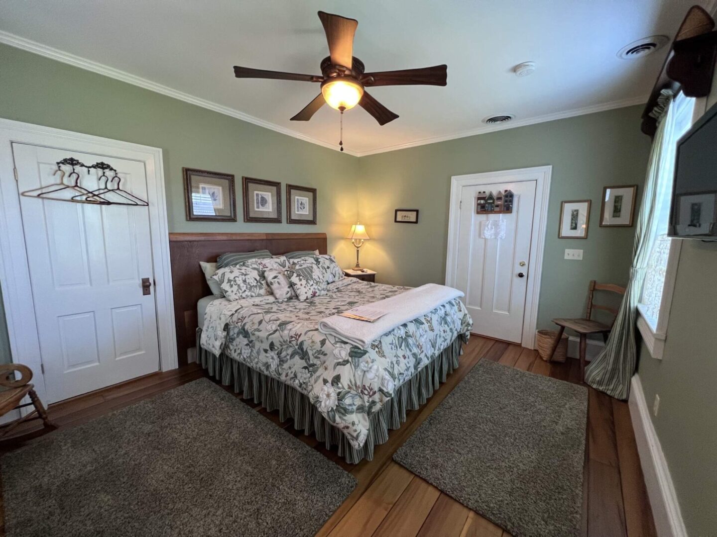 A bedroom with a bed, ceiling fan and two doors.