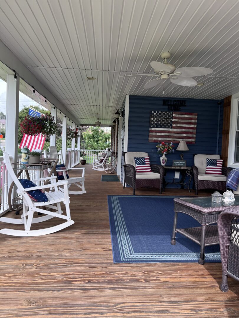 A porch with chairs, tables and american flag on the wall.