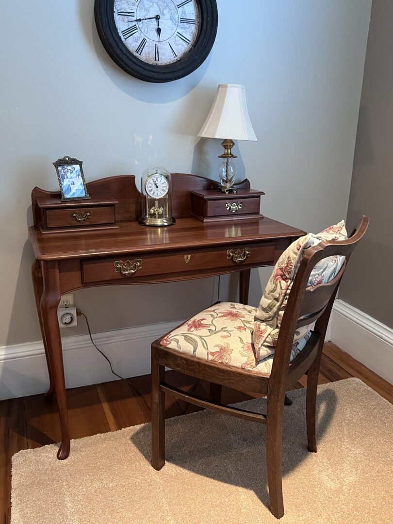 A desk with a chair and clock on the wall