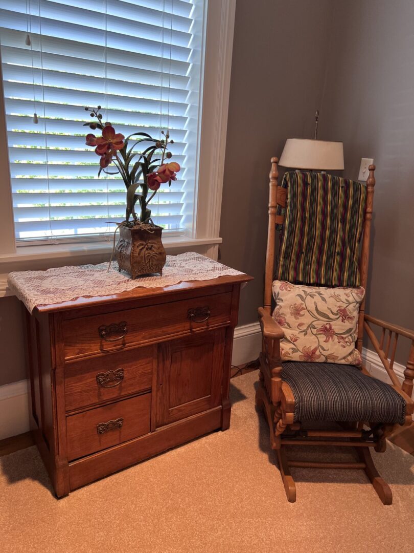 A chair and dresser in front of the window.