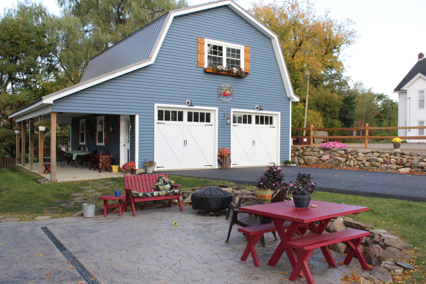 A blue garage with red benches and tables.